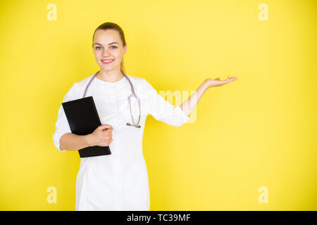 Junge weibliche blond Arzt mit Stethoskop an ihrem Hals und Tablet zeigt mit dem Finger auf einen Raum in Ihrer Nähe. Für text Stockfoto