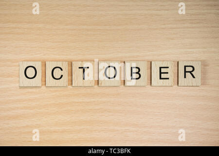 Das Wort Oktober, Dinkel mit Holz Fliesen auf einem Holz Wirkung Hintergrund. Stockfoto