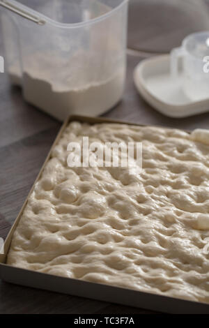 Handgefertigte Brot fermentiert italienische Pasta in forcaccia Backblech gelegt auf hölzernen Tischplatte Hintergrund mit Mehl focaccia Stockfoto