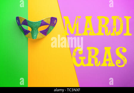 Festliche Maske mit Text MARDI GRAS (auch als Fat Tuesday bekannt) auf farbigen Hintergrund Stockfoto