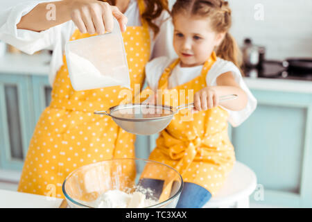 Selektiver Fokus von Mutter und Tochter sieben Mehl in Schüssel Stockfoto