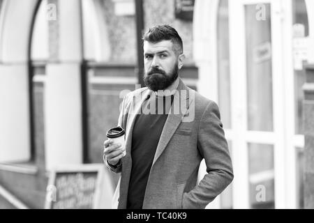 Geschäftsmann gepflegt aussehen genießen Sie Kaffee Pause aus Business Center. Entspannen und erholen Sie sich. Man bärtige hipster Pappbecher Kaffee trinken. Noch ein Schluck Kaffee. Kaffeegenuss unterwegs. Stockfoto