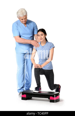 Reifen Physiotherapeuten arbeiten mit jungen asiatischen Frau auf weißem Hintergrund Stockfoto