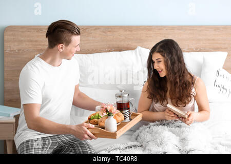 Junge Frau mit Frühstück im Bett von ihrem geliebten Mann Stockfoto