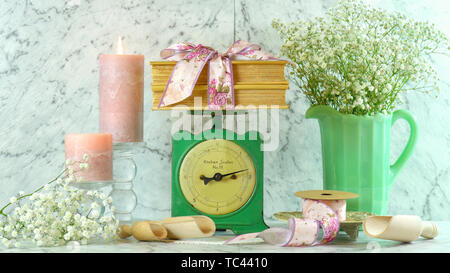 Vintage Küchenwaage Dekor Einstellung mit Porzellan Kanne gypsophila Blumen, Kerzen, Blumen Bänder und alte Bücher. Stockfoto