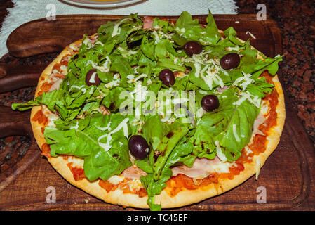 Lecker lecker Pizza mit Käse, Tomaten, Rucola, Oliven, Basilikum auf hölzernen Tisch Stockfoto