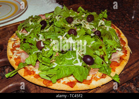 Lecker lecker Pizza mit Käse, Tomaten, Rucola, Oliven, Basilikum auf hölzernen Tisch Stockfoto