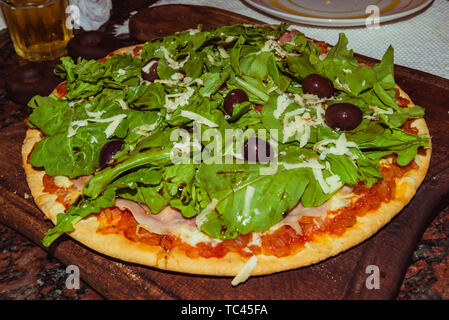 Lecker lecker Pizza mit Käse, Tomaten, Rucola, Oliven, Basilikum auf hölzernen Tisch Stockfoto