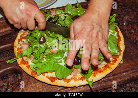 Lecker lecker Pizza mit Käse, Tomaten, Rucola, Oliven, Basilikum auf hölzernen Tisch Stockfoto