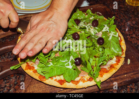 Lecker lecker Pizza mit Käse, Tomaten, Rucola, Oliven, Basilikum auf hölzernen Tisch Stockfoto