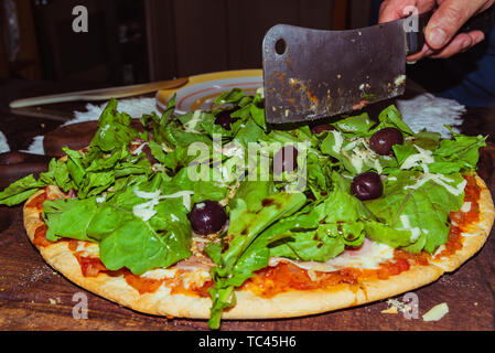 Lecker lecker Pizza mit Käse, Tomaten, Rucola, Oliven, Basilikum auf hölzernen Tisch Stockfoto