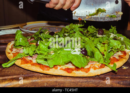Lecker lecker Pizza mit Käse, Tomaten, Rucola, Oliven, Basilikum auf hölzernen Tisch Stockfoto