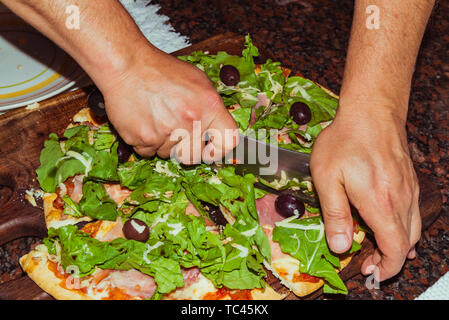 Lecker lecker Pizza mit Käse, Tomaten, Rucola, Oliven, Basilikum auf hölzernen Tisch Stockfoto