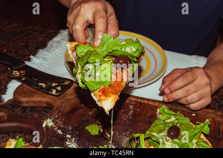 Lecker lecker Pizza mit Käse, Tomaten, Rucola, Oliven, Basilikum auf hölzernen Tisch Stockfoto