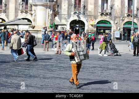 Catania, Sizilien, Italien - Apr 10 2019: älterer Mann Gaukler spielen Akkordeon auf der Piazza Duomo im Zentrum der Stadt. Kulturelle Straße Leistung. Stockfoto