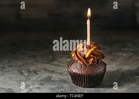 Leckere Schokolade cupcake Kerze auf grunge Hintergrund Stockfoto