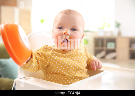 Süße kleine Baby mit lecker Essen zu Hause verschmiert Stockfoto