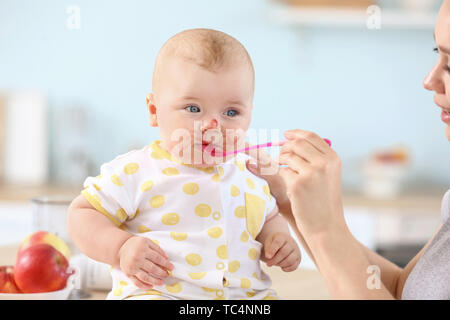 Mutter füttern Ihr kleines Baby in der Küche zu Hause. Stockfoto