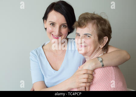Die alte Mutter mit erwachsener Tochter umarmen Portrait Stockfoto