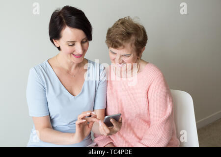 Junge Frau mit älteren weiblichen wie Smartphone zu verwenden Stockfoto