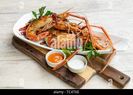 Nahaufnahme der gegrillt sautierte Big river Garnelen Fischplatte gemischter Salat pikanter Sauce Mayonnaise in einem Holz Brett fancy Platte isolierte natürliche Licht zurück Stockfoto