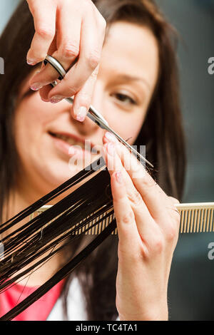 Friseur schneiden dunkle Haare mit professioneller Schere, die Pflege von Split Haar endet. Stockfoto