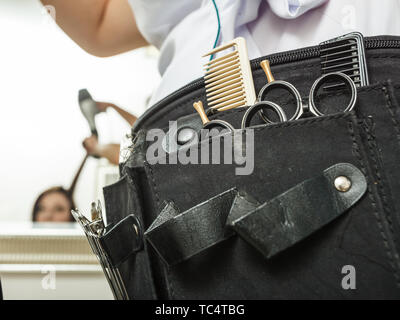 Friseur Ausstattung Konzept. Professionelle friseur Werkzeuge in schwarzen Gürtel. Scheren, Kämme und Clips. Stockfoto