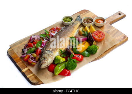 Nahaufnahme der gegrillten Mittelmeer bass ganze Fische isoliert Holzbrett natürliche zurück Licht gebratenes Gemüse gebackene Kartoffeln mischen Cherry Tomaten Basilikum Stockfoto