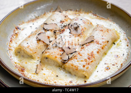 Nahaufnahme der italienischen Cannelloni Trüffeln Frische Pasta, schwarze Trüffel Ricotta, Parmesan Sahne auf eine trendige Fancy fashion Platte natürliche Back Light whi Stockfoto