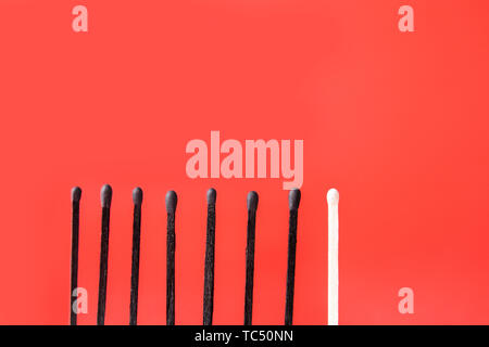 Eine unverbrannten Match zwischen ausgebrannten, die auf farbigen Hintergrund. Konzept der Einzigartigkeit Stockfoto