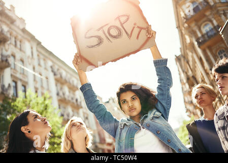 Macht Liebe, nicht Krieg. Starke junge Frau mit einem Namensschild in Wort Stop es ihr über den Kopf und stehen auf der Straße um Aktivistinnen. Rechte der Frau. März der Frauen. Menschenrechte Stockfoto