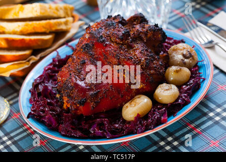 Bier knusprig gebratene ganze Schweinshaxe serviert mit gedünstetem Kohl und Zwiebel Stockfoto