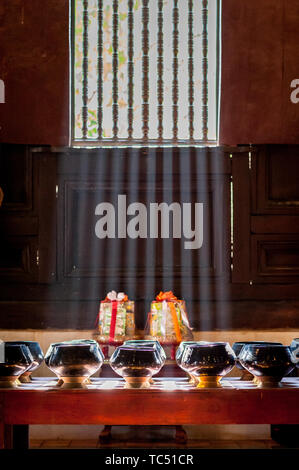 Sun Licht scheint durch die Fenster des Tempels auf Schalen aus Spenden von Gläubigen zu sammeln. Wat Phant Tao Tempel Chiang Mai. Thailand. Stockfoto
