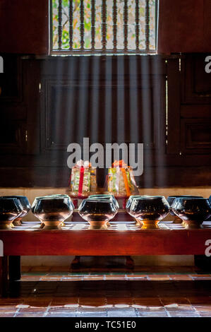 Sun Licht scheint durch die Fenster des Tempels auf Schalen aus Spenden von Gläubigen zu sammeln. Wat Phant Tao Tempel Chiang Mai. Thailand. Stockfoto