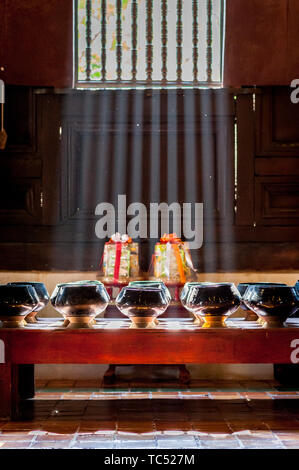 Sun Licht scheint durch die Fenster des Tempels auf Schalen aus Spenden von Gläubigen zu sammeln. Wat Phant Tao Tempel Chiang Mai. Thailand. Stockfoto