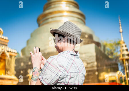 Ein Tourist nimmt ein Foto von der prunkvollen Tempelgestaltung im berühmten Wat Phra Sing Thai Temple Chiang Mai, Thailand, auf. Stockfoto