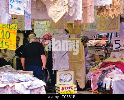 Istanbul, Türkei - 24.05.2010: Frauen mit Kopf Schals und männliche Verkäufer in einem Laden voller traditionelle weiße und bunte Spitze Tischdecken Tischsets Stockfoto