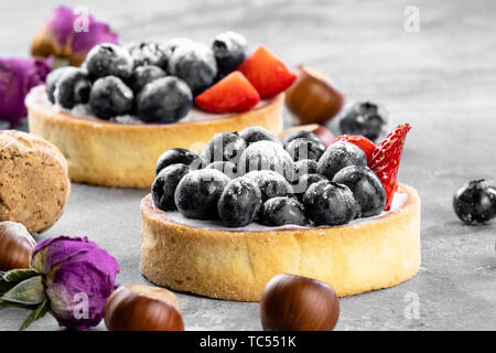 Blueberry, Strawberry Shortcake. Es gibt Haselnüsse, Rosen und Wein Korken auf dem Tisch. Stein grau hinterlegt. Stockfoto