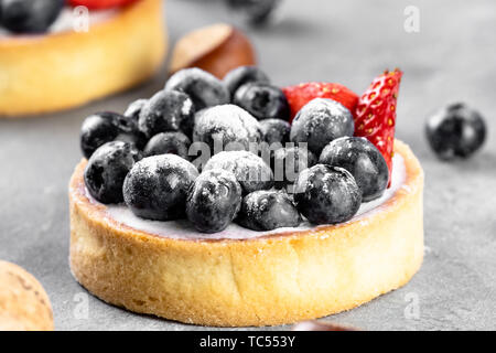 Blueberry, Strawberry Shortcake. Es gibt Haselnüsse, Rosen und Wein Korken auf dem Tisch. Stein grau hinterlegt. Stockfoto