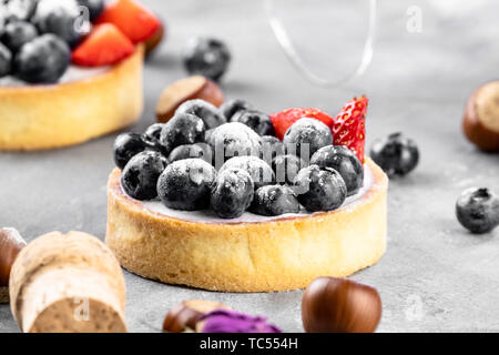 Blueberry, Strawberry Shortcake. Es gibt Haselnüsse, Rosen und Wein Korken auf dem Tisch. Stein grau hinterlegt. Stockfoto