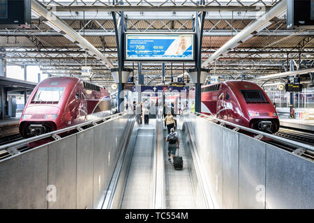 Passagiere ziehen ihre Koffer auf einen Bürgersteig zu Brett auf zwei Thalys Hochgeschwindigkeitszüge in Brüsseler Südbahnhof in Belgien. Stockfoto