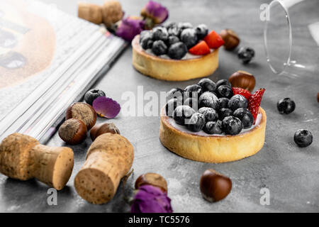 Blueberry, Strawberry Shortcake. Es gibt Haselnüsse, Rosen und Wein Korken auf dem Tisch. Stein grau hinterlegt. Stockfoto