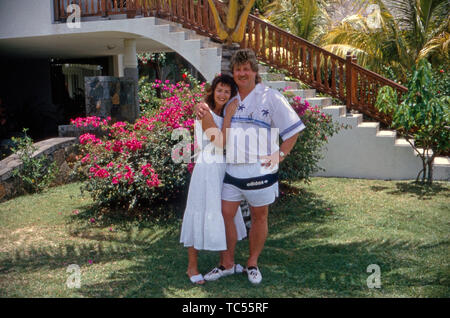 Der Sänger Klaus Baumgart posiert im Urlaub vermutlich auf den Bahamas im Außenbereich des Hotels mit seiner Ehefrau Ilona Schulz-Baumgart unter Palmen, Ca. 1970er. Der Sänger Klaus Baumgart stellt auf Ferien wahrscheinlich auf den Bahamas im Außenbereich des Hotels mit seiner Frau Ilona Schulz-Baumgart unter Palmen, über die 70er Jahre. Stockfoto