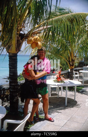 Der Sänger Klaus Baumgart posiert im Urlaub vermutlich auf den Bahamas im Außenbereich des Hotels mit seiner Ehefrau Ilona Schulz-Baumgart unter Palmen, Ca. 1970er. Der Sänger Klaus Baumgart stellt auf Ferien wahrscheinlich auf den Bahamas im Außenbereich des Hotels mit seiner Frau Ilona Schulz-Baumgart unter Palmen, über die 70er Jahre. Stockfoto