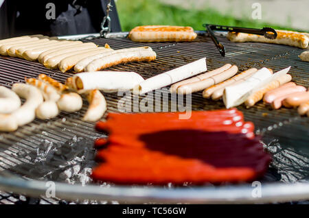 Verschiedene Arten von leckeren Würstchen auf dem Grill, BBQ. Grillen im Freien Stockfoto
