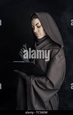 Frau in den Tod Kostüm holding Zwischenablage auf Schwarz Stockfoto