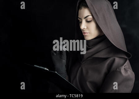 Frau in den Tod Kostüm holding Zwischenablage auf Schwarz Stockfoto