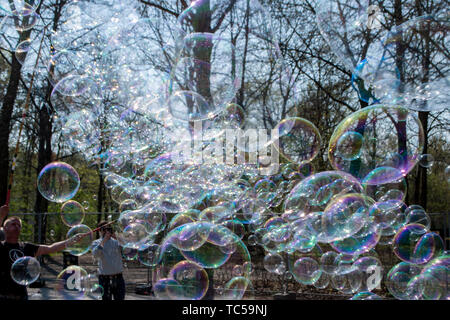 Berlin, Deutschland - 6. April 2019: Viele große Seifenblasen, die eine Person in einem Park ermöglicht, auf einer Straße in Berlin, in der Nähe des Reichstages. Es zieht viele t Stockfoto