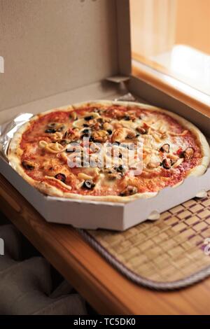 Box mit heißem köstliche italienische Pizza mit Meeresfrüchten auf der Fensterbank öffnen Stockfoto