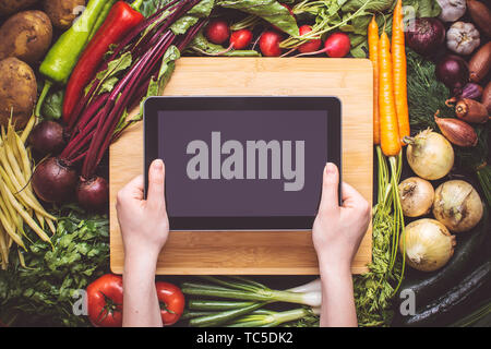 Hände mit Tablet über Frisches Bio-Gemüse Hintergrund. Vegetarische Rezepte. Stockfoto